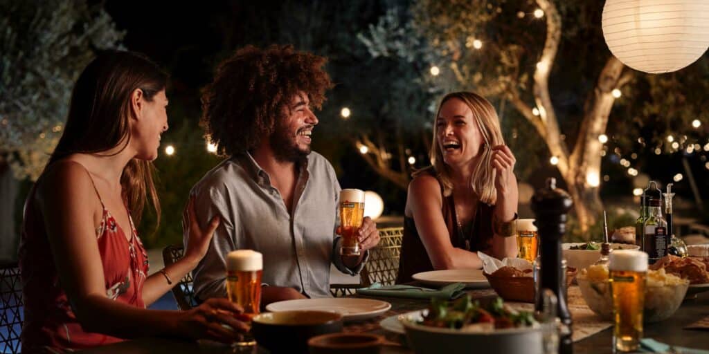 Twee vrouwen en man lachen met Heineken biertje